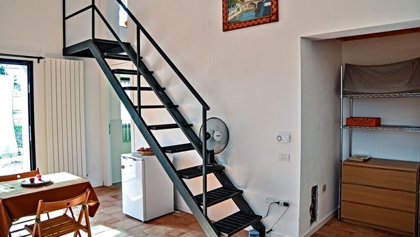 Un espacio habitable compacto con una escalera, un comedor y una pequeña cocina.