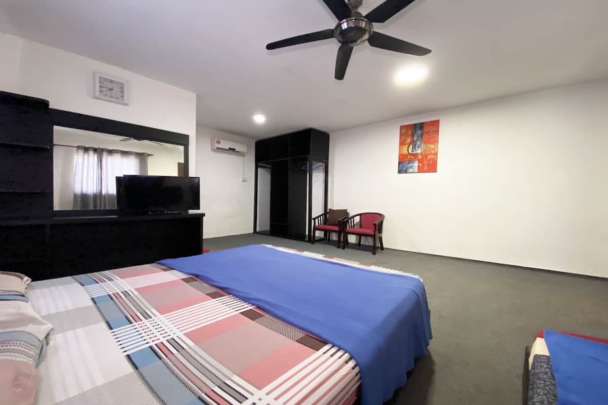 A hotel room with a bed, a desk with a computer, a chair, a ceiling fan, and a painting on the wall.