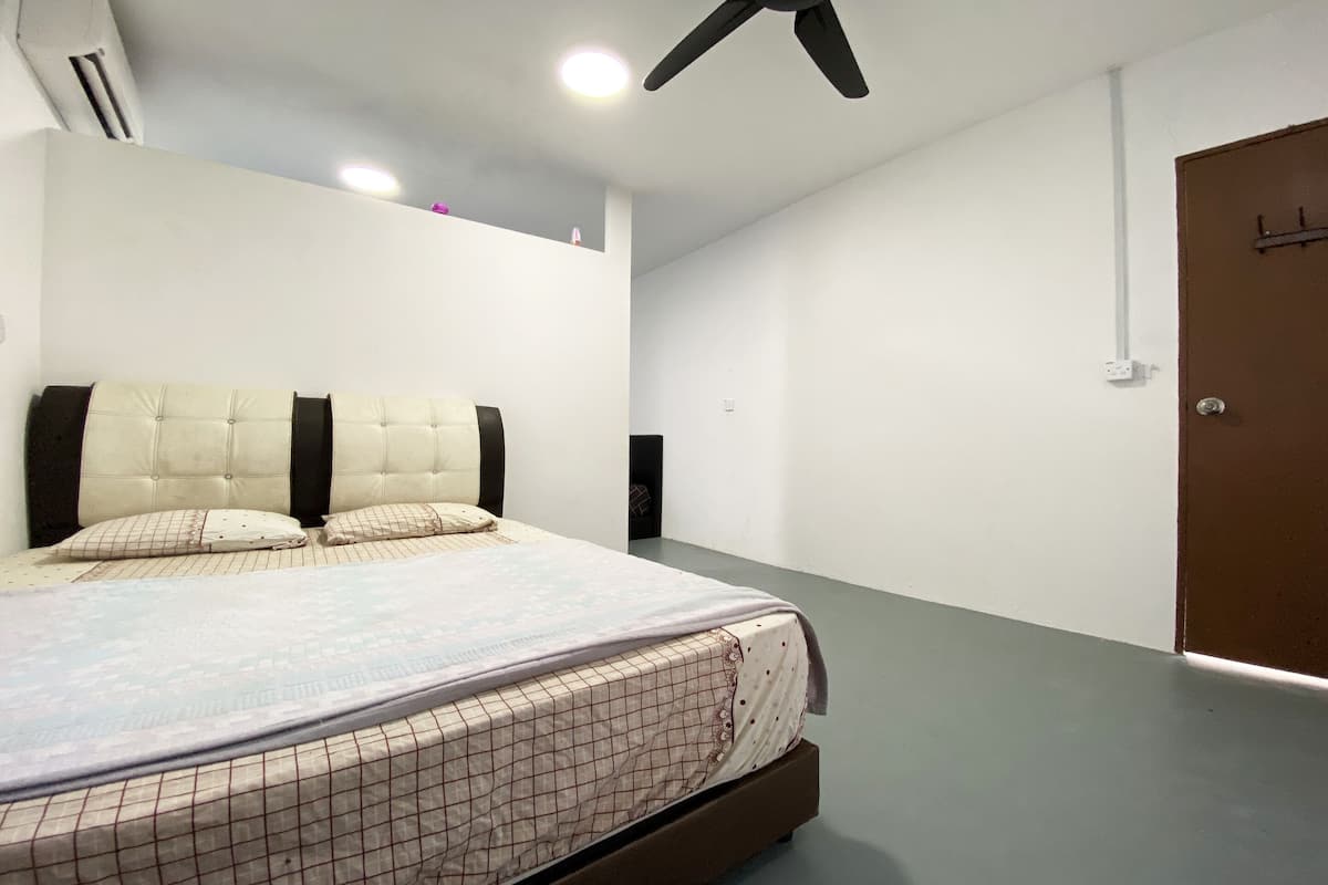 A bedroom with a bed, a ceiling fan, and a door.
