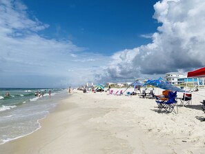 Una playa con arena, sombrillas y sillas.