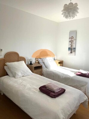 A hotel room with two beds, a nightstand, a lamp, and a wall-mounted sign.
