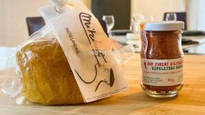 A loaf of bread wrapped in plastic, a jar of spice, and a paper bag with a logo. - Appt Ortolans - Hossegor center - Terrace - Park (Soorts-Hossegor)