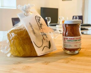 Ein Brot in Frischhaltefolie, ein Gewürzglas und eine Papiertüte mit einem Logo.
