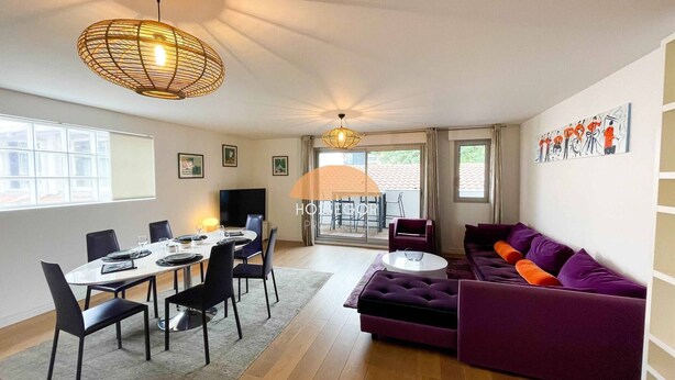 A modern living room with a dining area, a purple sofa, a round coffee table, and a large window. - Appt Ortolans - Hossegor center - Terrace - Park (Soorts-Hossegor)