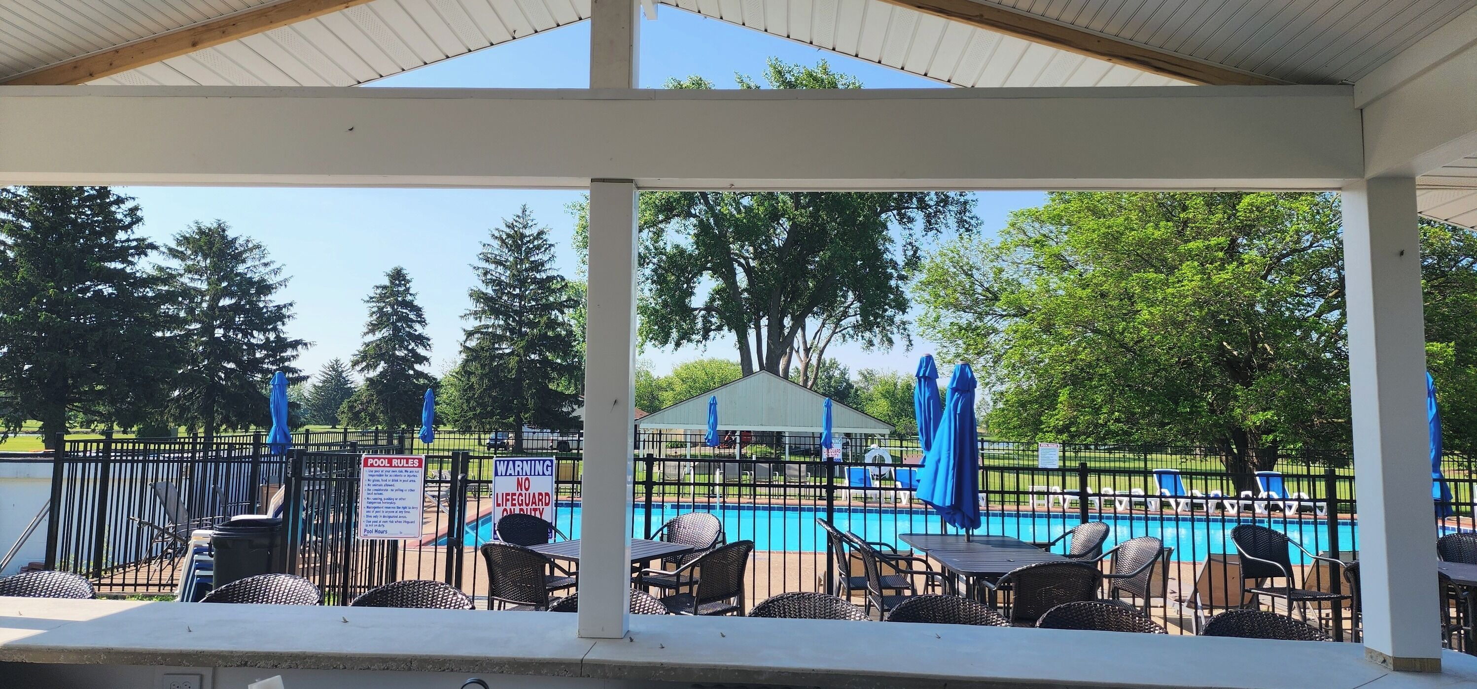 A covered outdoor area with a pool, chairs, and tables.
