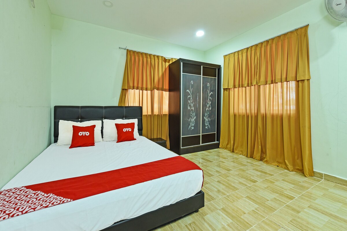 A neatly made bed with a red and white bedspread, two red pillows, and a black headboard.