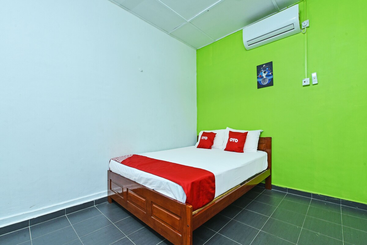 A single bed with a wooden frame, white bedding, and red accents.