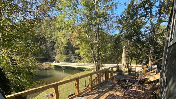 A hot tub on a wooden deck with a view of a lake and trees. - Watauga River Cottage in Johnson City, TN! (Johnson City)