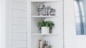 A white wooden cabinet with shelves, a plant, and decorative items. - Watauga River Cottage in Johnson City, TN! (Johnson City)