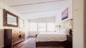 A bedroom with a large bed, wooden dresser, and a mirror. - Watauga River Cottage in Johnson City, TN! (Johnson City)