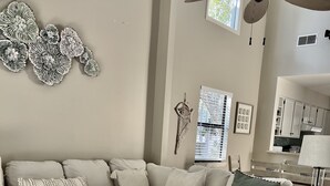 A modern living room with a sectional sofa, a coffee table, a ceiling fan, and a view of the kitchen. - Walk to the Beach from this New Bright 2BR/2B condo in the <3 of The Island  (Hilton Head Island)
