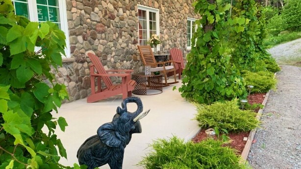 Un edificio de piedra con un patio que tiene sillas Adirondack rojas y una mesa pequeña.