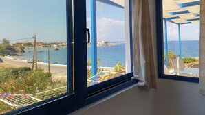 A room with a large window overlooking a coastal view, including a beach and the sea. - Sea View Holiday House (Archangelos)