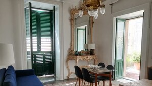 Una stanza con un divano blu, un tavolo da pranzo con sedie, un lampadario, uno specchio e una porta verde.