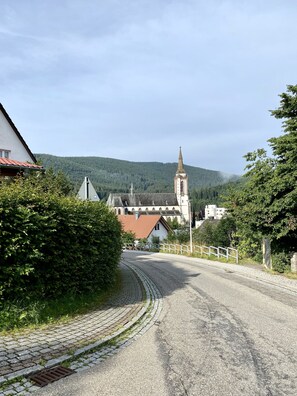A rural road leading to a church with a tall steeple, surrounded by greenery and a mountain in the background. - Exclusive 2-room loft apartment in Titisee-Neustadt (Titisee-Neustadt)