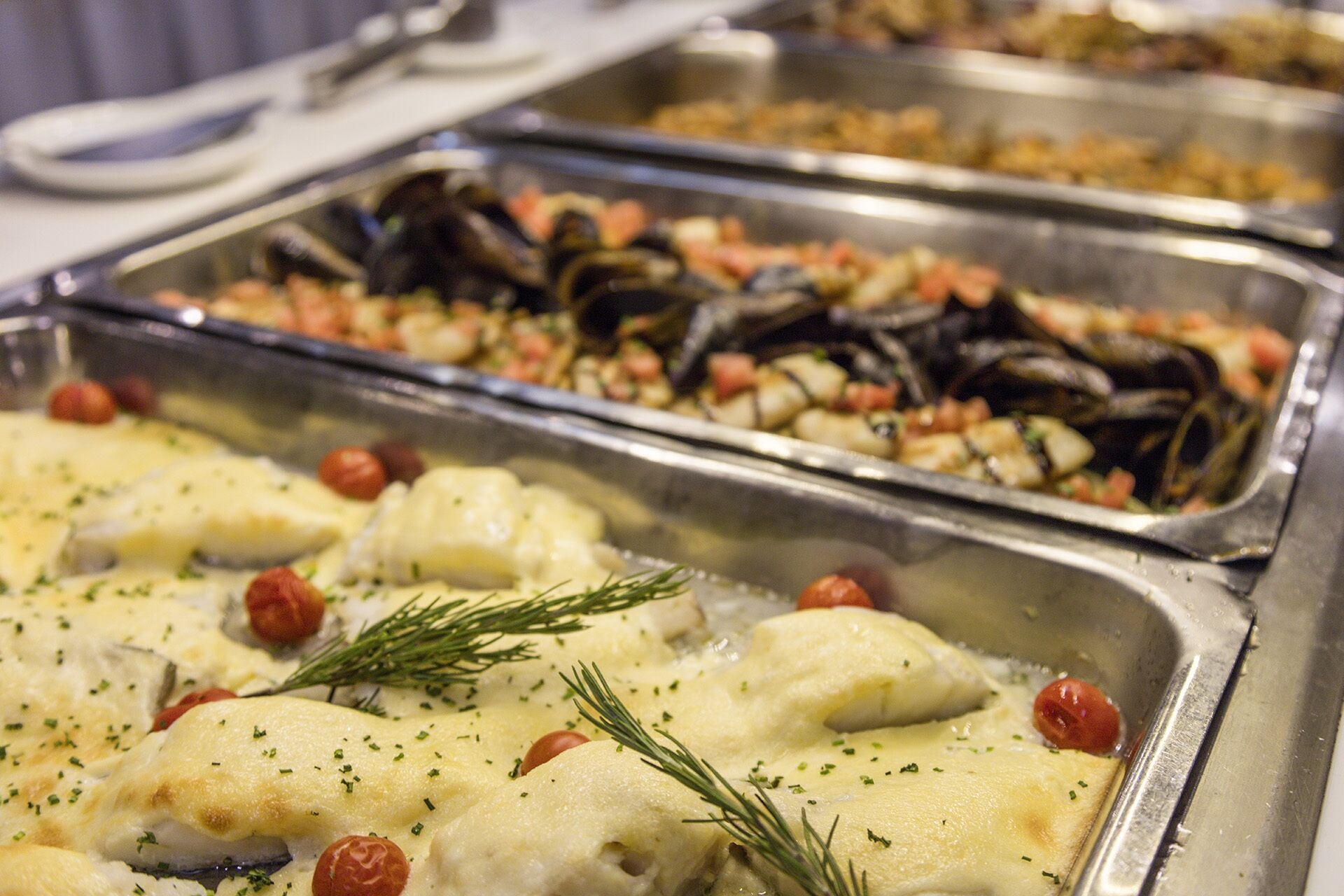 A buffet with seafood dishes, including mussels and fish, garnished with herbs.