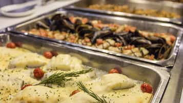 A buffet with seafood dishes, including mussels and fish, garnished with herbs.