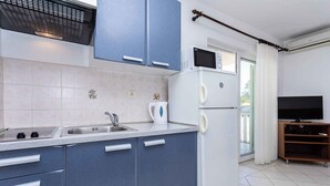 A modern kitchen with blue cabinets, a white refrigerator, a microwave, and a kettle. - Holiday apartment with a view of the mountains (Baška)