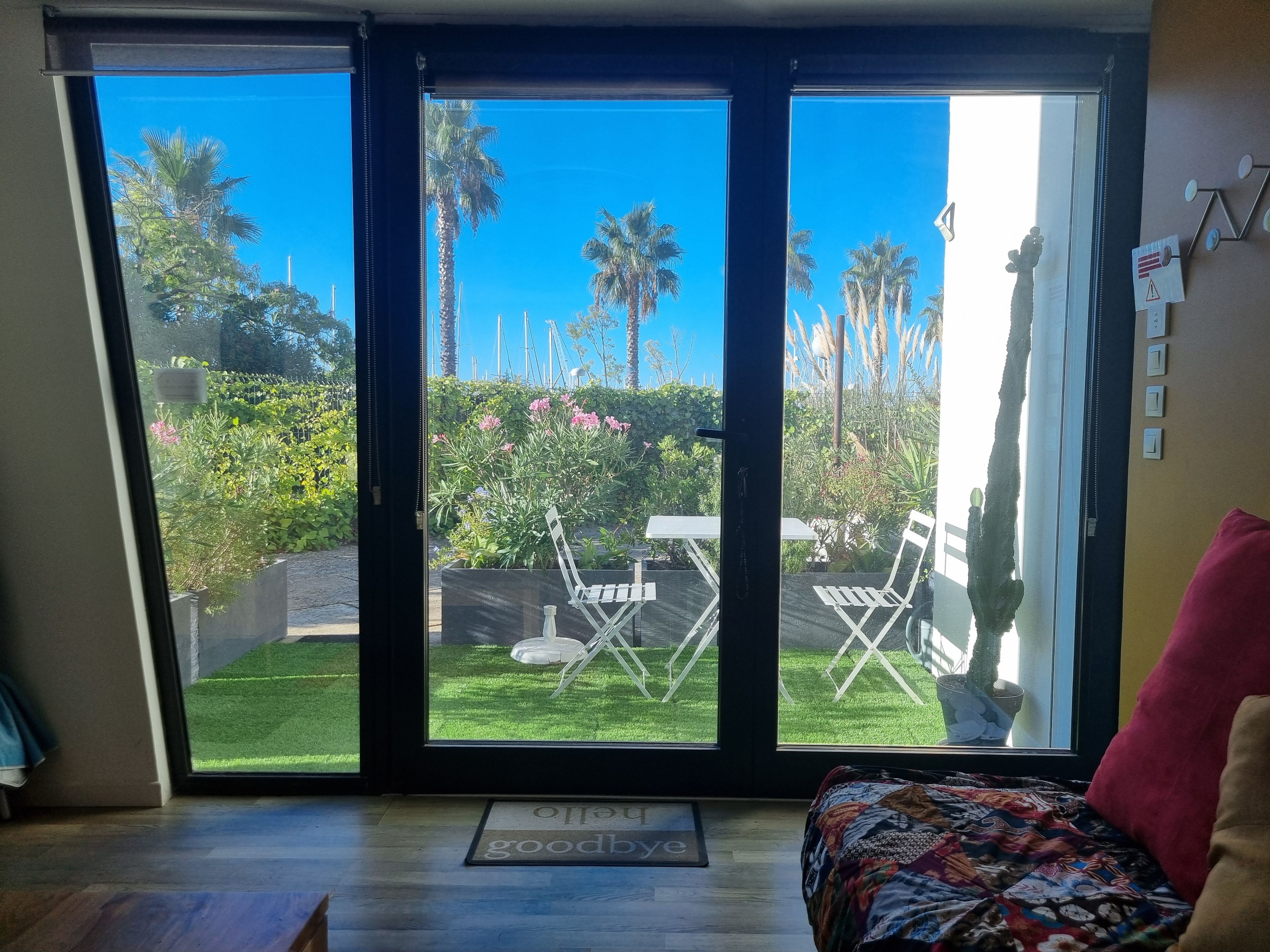 Ein Zimmer mit einer Glasschiebetür, die auf eine Terrasse mit Rasen, Stühlen und einem Tisch führt.