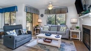 A living room with a grey sofa, a white coffee table, and a fireplace. - Charming Unit-11A St James-Full Amenity Access (Myrtle Beach)