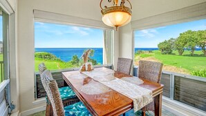 Un comedor con mesa, sillas y vista al océano.
