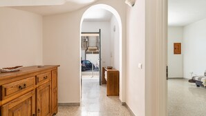 A hallway with a wooden cabinet, a small table, and a bed in the distance.