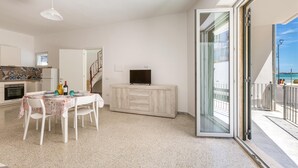 A modern apartment with a dining area, kitchen, and a balcony with a view.