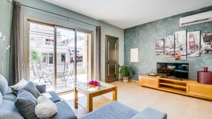 Un salon moderne avec un canapé, un téléviseur et un balcon donnant sur la rue.