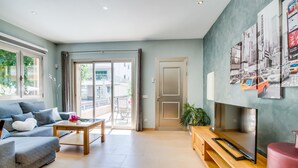 Un salon moderne avec un canapé, une table basse, un téléviseur et des œuvres d’art accrochées au mur.