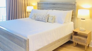 Una cama bien hecha con cabecera de madera, dos lámparas de noche y un ventilador de techo.