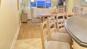Un comedor amplio con vista al océano, muebles de madera y una lámpara moderna.