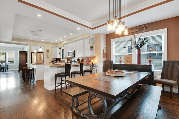 A spacious kitchen with white cabinets, a central island, and a dining area with a wooden table and chairs.