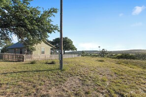 Situated on a grassy area, this single-story house offers a serene atmosphere with a large tree providing shade.