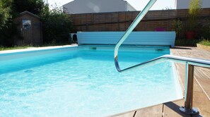 Relax by the pool surrounded by a deck and a fence.