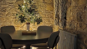 A dining area with a stone wall, a Christmas tree, and a modern chandelier. - Cobbles Cottage - 2 Bedroom Stone Built Cottage (Ballynahinch)