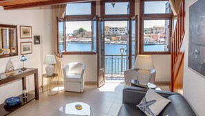 Een kamer met uitzicht op een haven, met een bank, een stoel, een tafel en een bijzettafel met decoratieve objecten.