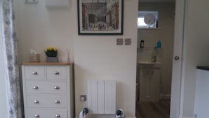 Ein Zimmer mit einem weißen Schminktisch, einem Heizkörper und zwei dekorativen Figuren auf dem Boden.