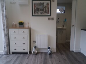 A room with a white dresser, a radiator, and two decorative figures on the floor. - Rose View - Modern Detached Bungalow (Sale)