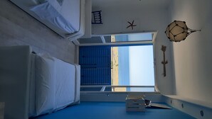 A room with a large window, a bed, a desk, and a wall-mounted decorative item.