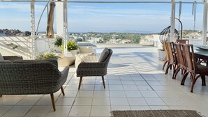A covered outdoor seating area with wicker furniture and a view of the city and sea. - Villasonboard 3 Bedroom Penthouse Vouliagmeni (Vari-Voula-Vouliagmeni)