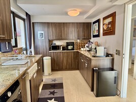 A compact kitchen with wooden cabinets, a microwave, a coffee maker, and a refrigerator.