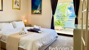 A bedroom with two beds, a large window with a view, and artwork on the walls. - Villasonboard 3 Bedroom Penthouse Vouliagmeni (Vari-Voula-Vouliagmeni)