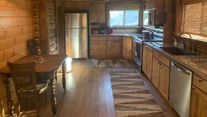 L’intérieur d’un chalet rustique en bois comprend une cuisine équipée d’un réfrigérateur, d’une cuisinière, d’un évier et d’armoires en bois.