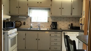 A compact kitchen with white cabinets, a stove, a microwave, and a sink. -  Reduced to $90.00 March-July week days (Byrnedale)
