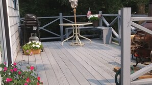A wooden deck with a table and chairs, surrounded by potted plants and a barbecue grill. -  Reduced to $90.00 March-July week days (Byrnedale)