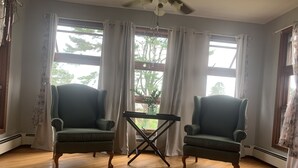 Quarto com duas poltronas, uma mesinha e um ventilador de teto.