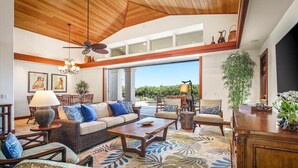 A spacious living area with a high ceiling, wooden ceiling, and large windows. There are multiple seating arrangements including a sofa, chairs, and a coffee table. - Luxury 4 Bedroom with private pool & Spa (Waimea)