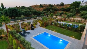 Une piscine rectangulaire entourée d’un patio comprenant un barbecue et des chaises longues.