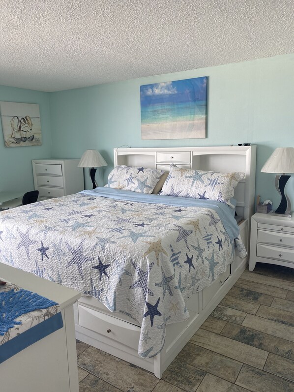 A bedroom with a bed, nightstands, a desk, and a chair.