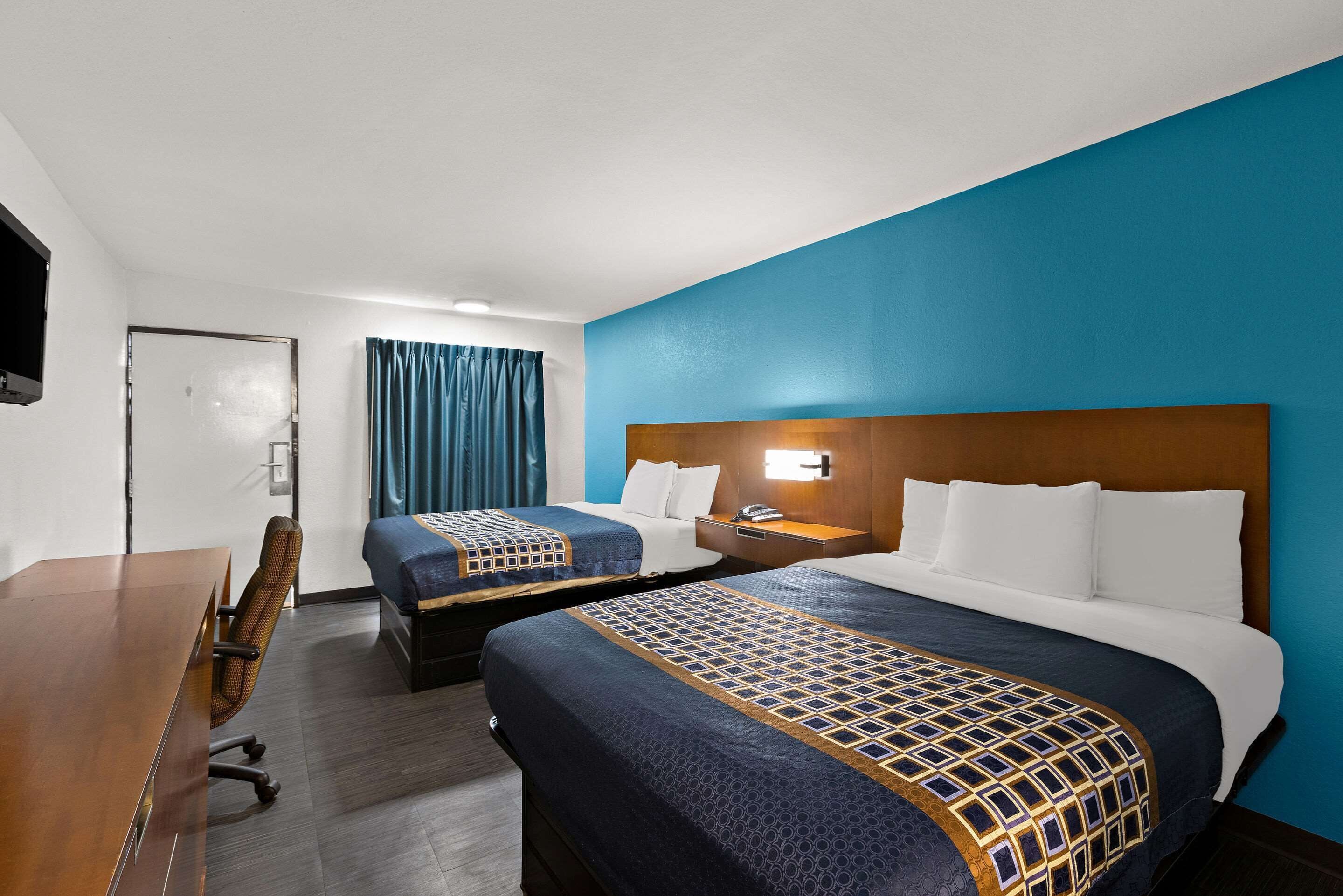 A hotel room with two beds, a desk, and a chair.